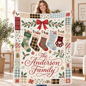 May include: A quilted throw blanket featuring a cream background with a border of assorted holiday-themed patches. The center displays five hanging Christmas stockings labeled Dad, Mom, Leo, Lily, and Buddy, topped with a red bow and the text The Anderson Family.