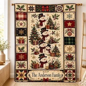 Puede incluir: Un tapiz acolchado rectangular con un panel central de cuatro muñecos de nieve, árboles de Navidad y regalos. El borde consta de cuadrados con acebo, copos de nieve, patrones de cuadros y estrellas. El texto dice The Anderson Family.