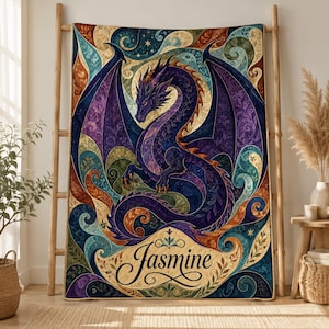 May include: A rectangular throw blanket featuring a large, central purple dragon with spread wings, surrounded by intricate swirling patterns in shades of blue, gold, and green. The name Jasmine is printed in black script at the bottom.