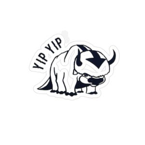 May include: A black and white sticker featuring a cartoon bison-like creature with the text "YIP YIP" above it. The creature has large horns, a prominent arrow-shaped marking on its head, and a determined expression.