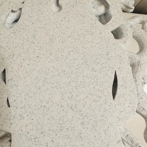 K&ouml;nnte beinhalten: Ein wei&szlig;es, gesprenkeltes Dekorationsobjekt mit einem Medusenhaupt-Design. Die Skulptur weist komplizierte Details auf, darunter sich windende Schlangen und eine strukturierte Oberfl&auml;che. Das Objekt hat ein gesprenkeltes Muster aus schwarzen und grauen Punkten.