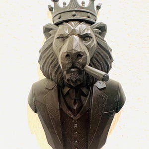 May include: A black lion bust wearing a crown, suit jacket, and vest, with a cigar in its mouth. The sculpture has a geometric design and is set against a neutral background. The lion's mane is detailed.