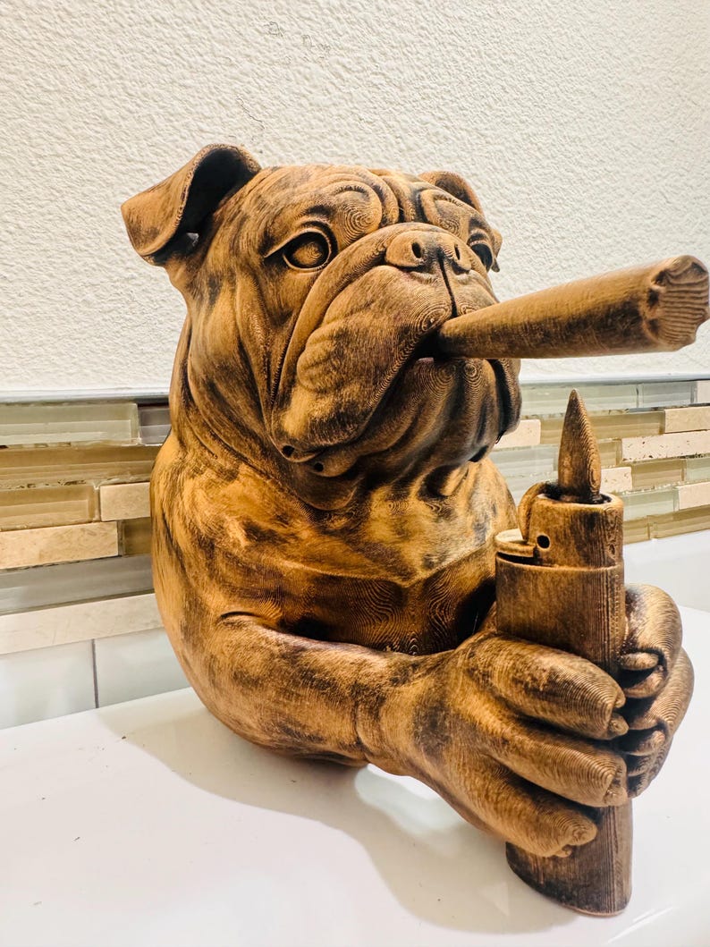 May include: A brown bulldog sculpture with a cigar in its mouth and a lighter in its hand. The sculpture has detailed textures and a realistic appearance, with a light source casting shadows.