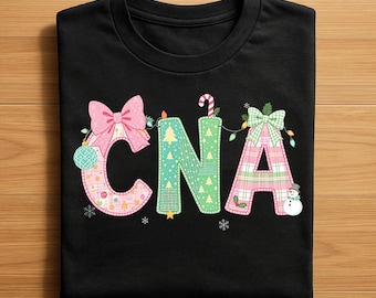 Może przedstawiać: Czarny t-shirt z literami "CNA" w świątecznym wzorze. Litery zdobią kokardy, lampki choinkowe i bałwanek. Litera "C" ma różową kokardę, "N" ma laseczkę cukrową, a "A" ma zieloną kokardę.