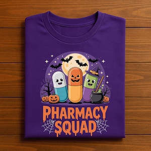 May include: A purple t-shirt featuring a Halloween-themed design. The graphic includes three cartoon capsules with jack-o'-lantern faces, bats, a full moon, and the words "PHARMACY SQUAD" in orange. The design is set against a spooky night scene.
