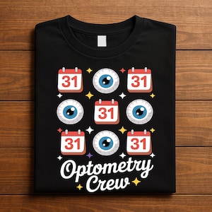 Puede incluir: Camiseta negra con un diseño que presenta el número 31 en calendarios y globos oculares. Las palabras "Optometry Crew" están escritas en una fuente estilizada debajo de los gráficos. Formas de estrellas amarillas están dispersas alrededor del diseño.