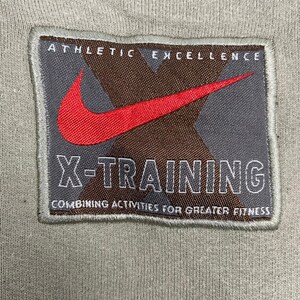 May include: A gray patch with the Nike swoosh logo in red, and the text "X-TRAINING" in white. The patch also includes the words "ATHLETIC EXCELLENCE" and "COMBINING ACTIVITIES FOR GREATER FITNESS".