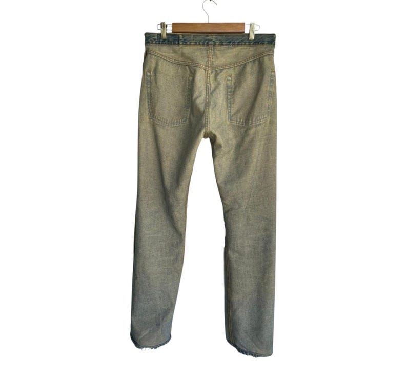 May include: Back view of faded denim jeans hanging on a wooden hanger. The jeans have a light wash with visible wear and tear, featuring two back pockets and a classic straight leg design. The waistband is a darker shade of blue.