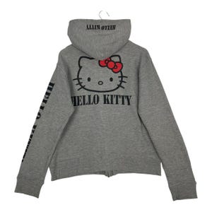 May include: Grey zip-up hoodie with a Hello Kitty graphic on the back, complete with a red bow. The hood and back of the hoodie display the words "HELLO KITTY". The left sleeve also features the words "HELLO KITTY" printed vertically.