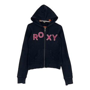 May include: A navy blue zip-up hoodie with a hood and two front pockets. The word "ROXY" is printed across the chest in pink letters with a white outline. The hoodie has a full zipper and long sleeves.
