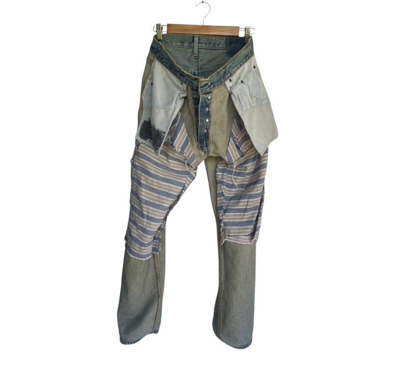 May include: Distressed denim jeans with patchwork detailing. The jeans feature a light blue wash with various fabric patches, including striped and solid sections. The design includes visible seams and a button fly, creating a unique, deconstructed aesthetic.