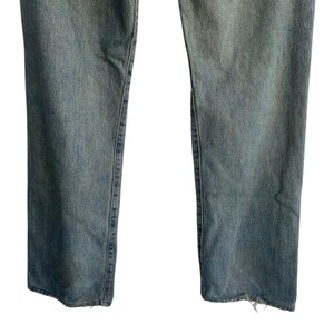 May include: Light blue denim jeans with a straight leg cut. The jeans have a faded wash and a distressed hem. The image shows the lower portion of the jeans, from the knees down.