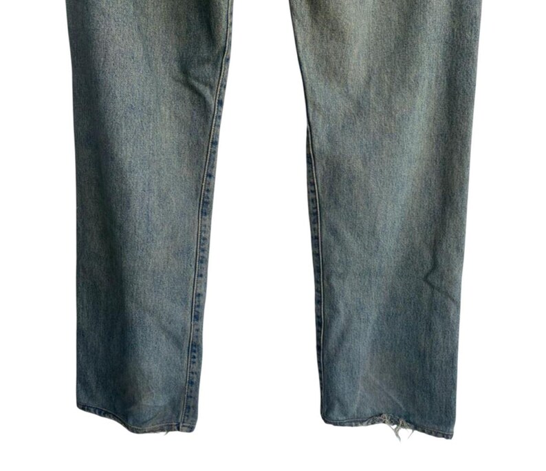 May include: Light blue denim jeans with a straight leg cut. The jeans have a faded wash and a distressed hem. The image shows the lower portion of the jeans, from the knees down.