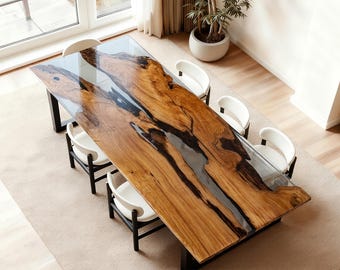 May include: A large, rectangular wooden dining table with a clear epoxy resin river running through the center. The table is surrounded by six white chairs with black legs. The table is approximately 100 inches long.