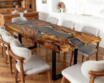 May include: A large, rectangular dining table with a live edge wooden top and a dark gray epoxy resin center. The table is supported by black metal legs. Surrounding the table are eight gray upholstered chairs with wooden frames.
