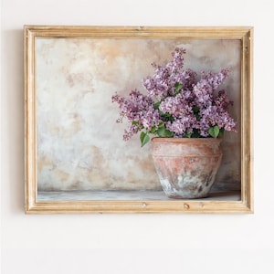 Peut inclure: Nature morte encadrée avec un pot en terre cuite rempli de lilas violets vibrants. Le pot repose sur une étagère contre un fond texturé aux tons neutres. Le cadre est de couleur brun clair et chaud, ajoutant une touche rustique.