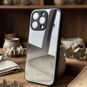 May include: A smartphone case with a black frame and a reflective, swirling gray and white design. The case has a camera cutout with multiple lenses and the word "concorvellies" printed at the bottom.