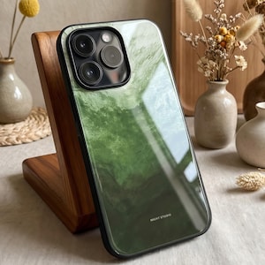 Könnte beinhalten: Smartphone-Hülle mit grünem Marmormuster. Die Hülle hat einen schwarzen Rand und eine glänzende Oberfläche. Die Kameralinsen sind sichtbar. Der Text "MIGHT STUDIO" ist auf der Unterseite der Hülle aufgedruckt.