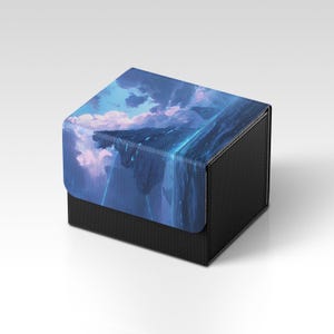 May include: A black box with a textured surface. The lid features a digital art design of a fantasy landscape with blue and purple hues, including clouds and glowing lines.