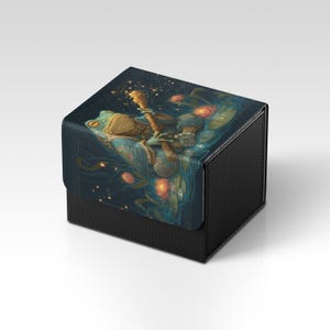 Può includere: Scatola nera con superficie strutturata. Il coperchio presenta un'illustrazione fantasy di una rana che cavalca una creatura attraverso una notte stellata. L'opera d'arte include colori caldi e un design stravagante.