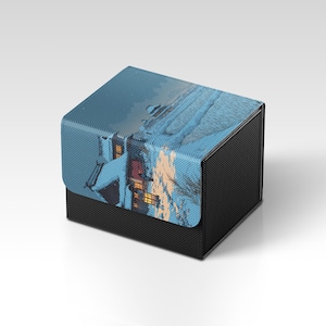 May include: A black box with a textured exterior and a lid featuring a winter scene with snow-covered buildings and warm interior lights. The lid's image has a blue and white color scheme.