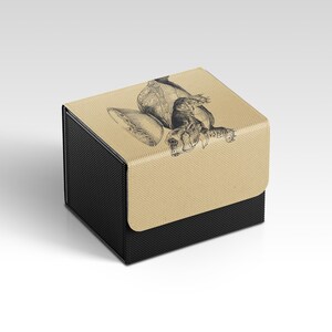 May include: A black and tan box with a hinged lid. The lid features a detailed black and white illustration of a turtle. The box has a textured appearance.