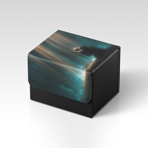 Könnte beinhalten: Eine schwarze Box mit strukturierter Oberfläche. Der Deckel zeigt ein digitales Kunstdesign in Türkis- und Goldtönen. Die Box ist quadratisch und scheint aus strapazierfähigem Material zu sein.