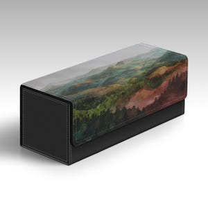 May include: A rectangular storage box with a black textured base and a lid featuring a printed landscape illustration of rolling green hills, dark forests, and a distant mountain range under a soft, overcast sky with visible stitching details.