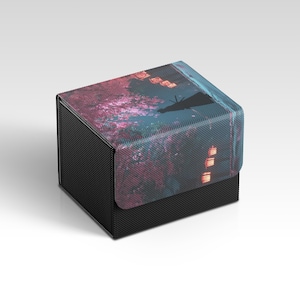 May include: A black box with a textured surface and a lid featuring a colorful design. The lid displays a scene with pink and blue hues, possibly depicting a landscape with lanterns and a silhouette.