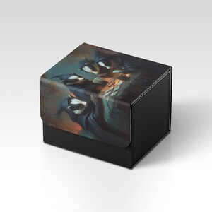 Könnte beinhalten: Eine schwarze, strukturierte Box mit einem Klappdeckel. Der Deckel zeigt ein farbenfrohes, abstraktes Design mit Blau-, Orange- und Weißtönen. Die Box hat eine quadratische Form und ein mattes Finish.