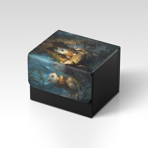 Könnte beinhalten: Schwarze Aufbewahrungsbox mit einer detaillierten Illustration von mausartigen Kreaturen in einer Waldszene. Die Box hat eine strukturierte Oberfläche und einen Klappdeckel, ideal zur Aufbewahrung kleiner Gegenstände.