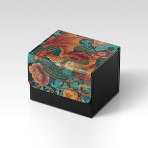 Könnte beinhalten: Eine schwarze Box mit strukturierter Oberfläche und detailliertem Design auf dem Deckel. Der Deckel zeigt einen Drachen mit orangefarbenen und roten Schuppen, umgeben von floralen Mustern in Türkis, Orange und Gold. Die Box ist wahrscheinlich für die Aufbewahrung oder Präsentation gedacht.