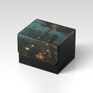 May include: A black, textured box with a hinged lid. The lid features a detailed, atmospheric illustration of a cityscape at night, with warm lights and a misty, teal-toned sky. The box is likely for storage or display.