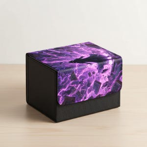 Könnte beinhalten: Eine schwarze Aufbewahrungsbox mit einem lila Blitzdesign auf dem Deckel. Die Box ist rechteckig und steht auf einer hellen Holzoberfläche. Der Deckel zeigt ein lebendiges Muster aus lila Blitzen.