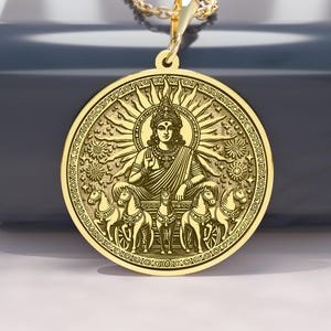 May include: A gold-colored pendant necklace featuring a detailed circular medallion. The medallion depicts a seated figure surrounded by intricate designs and sun rays. The necklace chain is also gold-colored, creating a cohesive and elegant look.