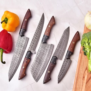 May include: An overhead shot showcases a set of six kitchen knives with dark wooden handles and textured blades. The knives are arranged near fresh produce, including a yellow bell pepper, a red bell pepper, an onion, and a head of broccoli.