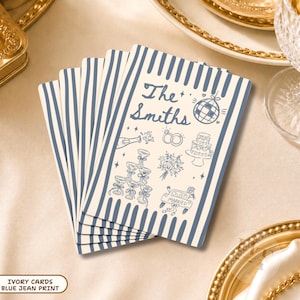 May include: A stack of ivory rectangular cards featuring a blue striped border and blue line art illustrations including a disco ball, wedding rings, a tiered cake, a champagne tower, a bouquet, and a car with the text The Smiths and Just Married.