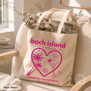 May include: A beige canvas tote bag featuring a bright pink graphic print. The text reads "bach island", "a bride has entered the villa", and "SAMANTHA'S BACHELORETTE EST. 2026 WEST PALM BEACH, FL". The design includes a heart, palm trees, and a cocktail.
