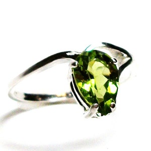 May include: A silver ring with a pear-shaped green gemstone