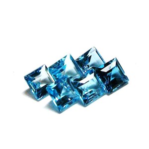 May include: Six square-shaped, faceted, blue topaz gemstones. The gemstones are arranged in a staggered pattern.