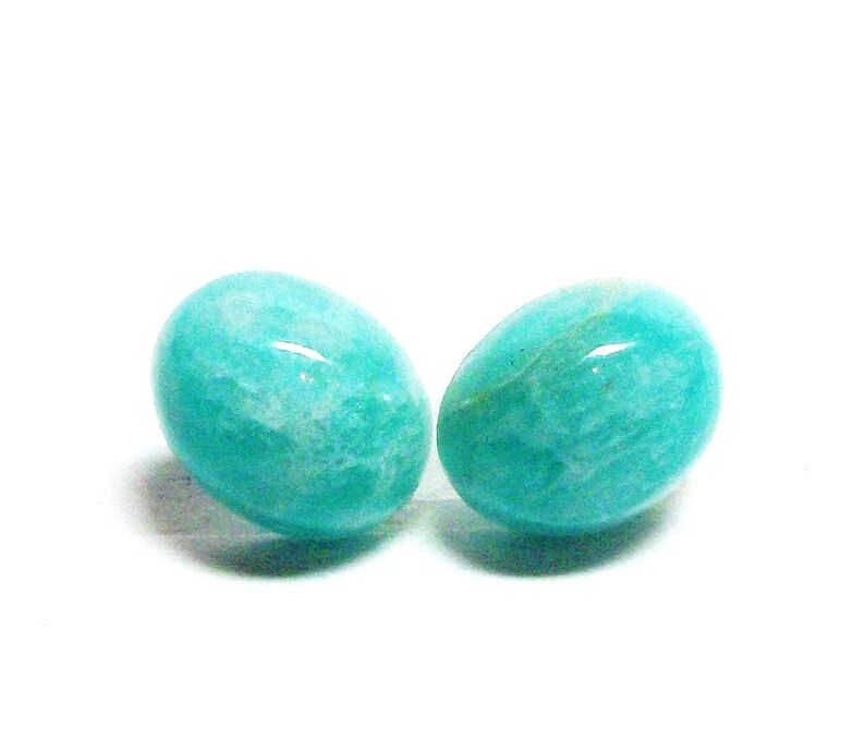 May include: Two oval-shaped teal green gemstones, likely amazonite, with a smooth, polished finish.