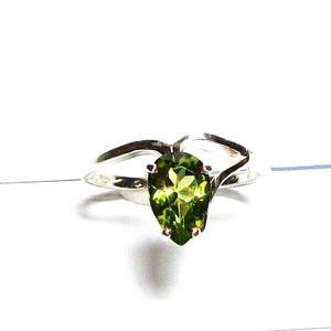 May include: A silver ring featuring a pear-shaped green gemstone.