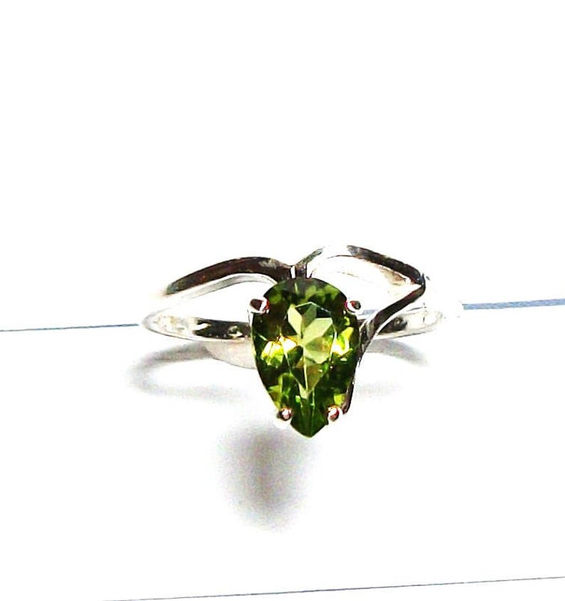May include: A silver ring featuring a pear-shaped green gemstone.