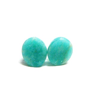 May include: Two round, teal green gemstone earrings. The earrings are smooth and have a slightly mottled appearance.