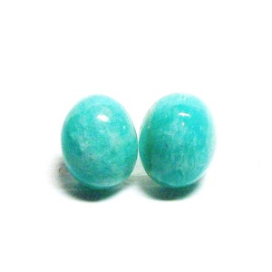 May include: A pair of round, turquoise green gemstone earrings. The earrings are made of smooth, polished stones.