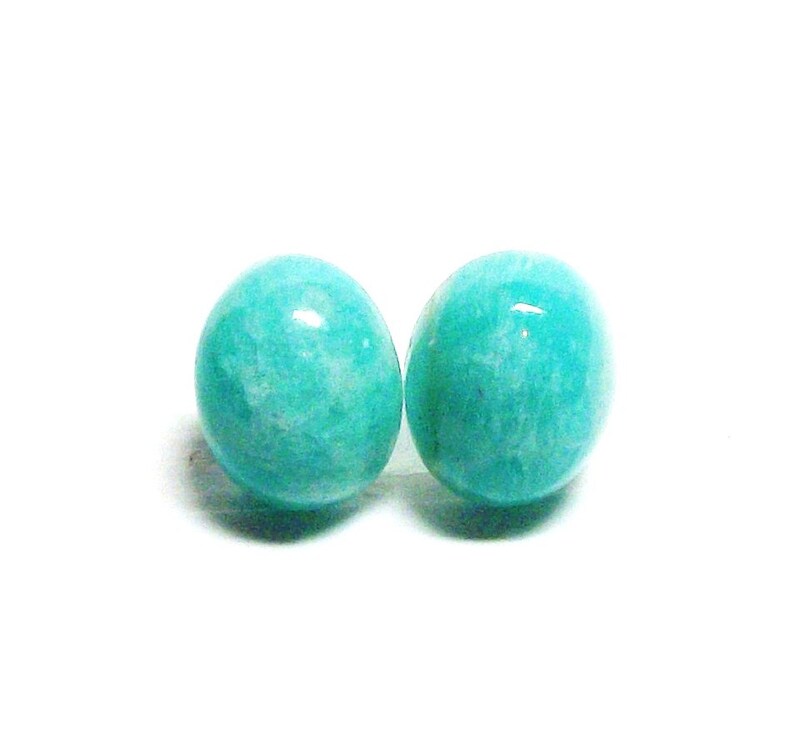 May include: A pair of round, turquoise green gemstone earrings. The earrings are made of smooth, polished stones.