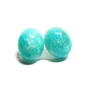 May include: A pair of teal green gemstone earrings. The earrings are round and have a smooth, polished finish.