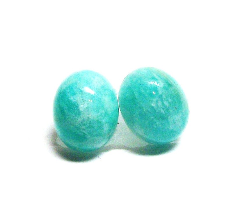 May include: A pair of teal green gemstone earrings. The earrings are round and have a smooth, polished finish.