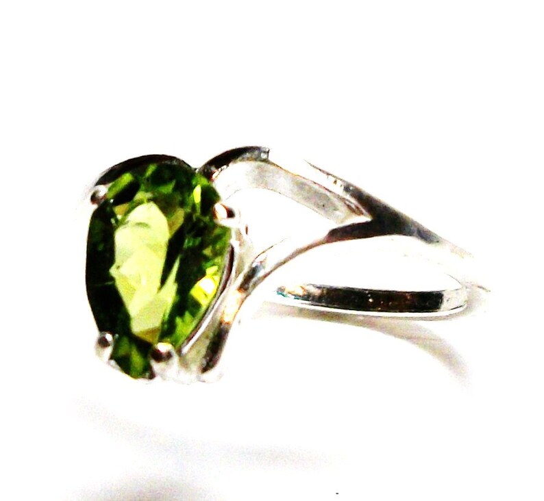 May include: A silver ring with a pear-shaped green gemstone.