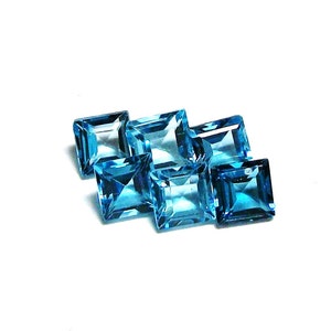 May include: Six square-shaped, faceted, blue topaz gemstones. The gemstones are arranged in a staggered pattern.